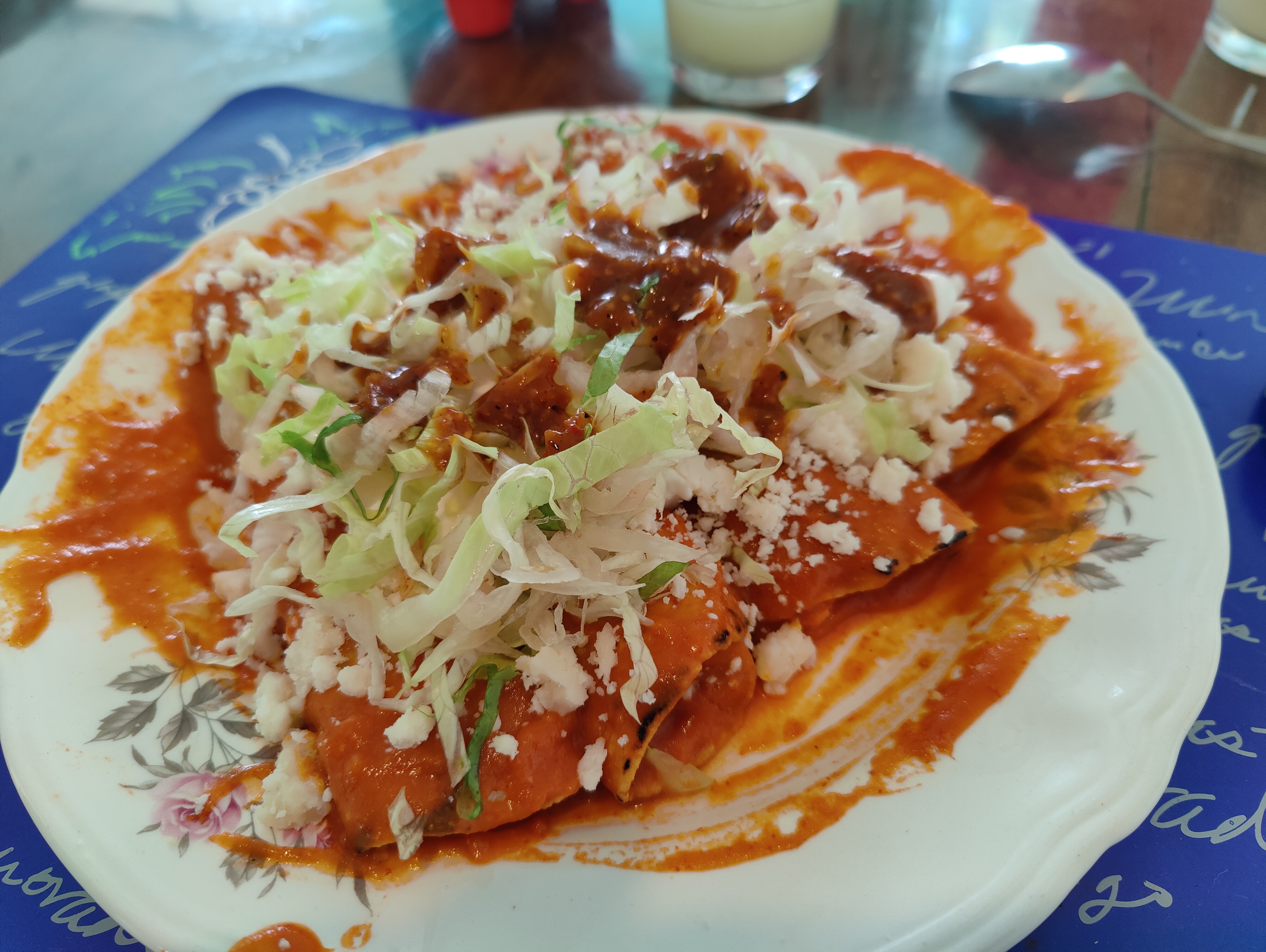 Red enchiladas served with cheese and chopped lettuce on top